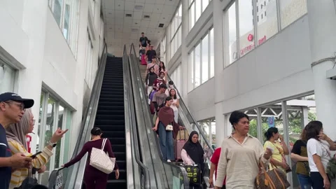 Crowd of passengers descending an escalator inside a station Видео 333836858