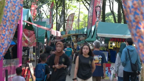 Crowd of people browsing food stalls at a busy outdoor night bazaar Stock Footage 346349944