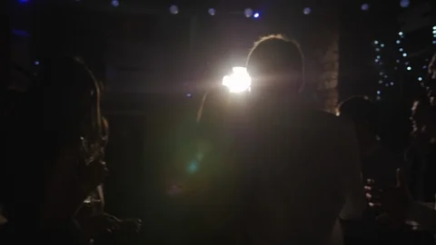 A crowd of people dancing at a party in the dark silhouettes rays of light Stock Footage 111516647