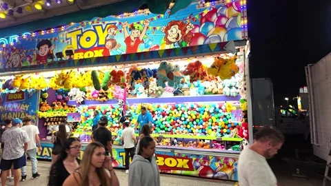 Crowd of people enjoying a fun night at the midway playing booth games for Vídeo Stock 344470311