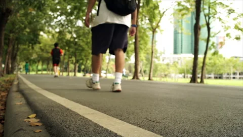 A crowd of people exercising and riding bikes through a lush park 動画素材 283707624