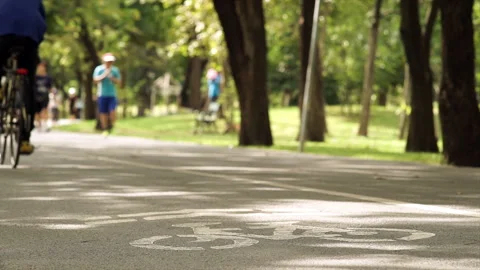 A crowd of people exercising and riding bikes through a lush park Video stock 283711036