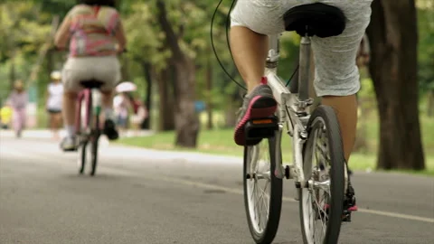 A crowd of people exercising and riding bikes through a lush park 動画素材 283711413