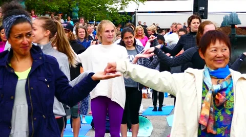 Crowd of people forming a human chain holding hands united doing meditation yoga Stock Footage 63933659