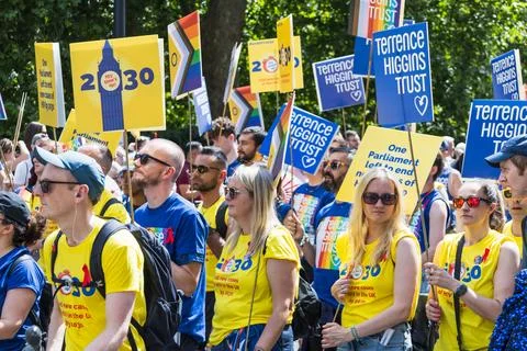 Crowd of people marching in a pride parade with signs and flags. London, UK, 29 库存照片