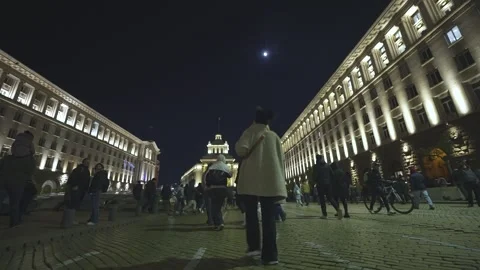 A crowd of people move at night along a boulevard in the center of Sofia 스톡 동영상 324563971