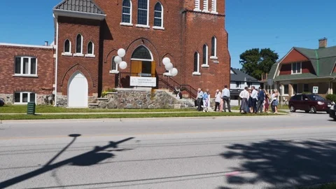 Crowd of people outside of a beautiful brick church during a wedding. Video stock 101711182