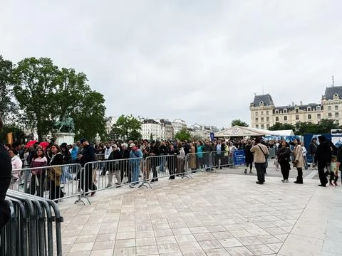 Crowd of people queuing behind barriers at an outdoor event in Paris, Franc.. Foto stock