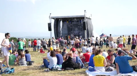 Crowd people spectators sit rest relax on rugs listen to music open air festival Stock Footage 64742045