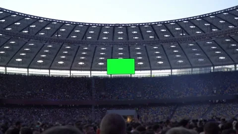 Crowd of people stand in an open stadium with Big TV Green Screen Stock Footage 112835505