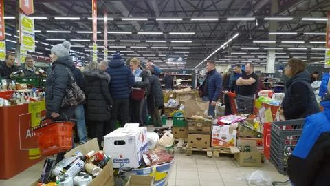 Crowd of people in a store. Clutter, trash and scattered goods on a dirty floor. Stock Photos