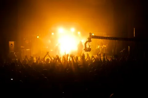Crowd of people with their hands up in front of the stage during the concert Stock Photos