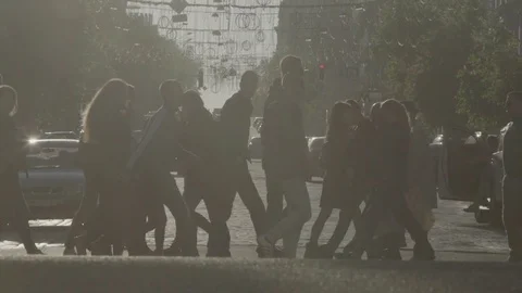 A crowd of people walk along the pedestrian crossing at sunset. Slow Motion. Stock Footage