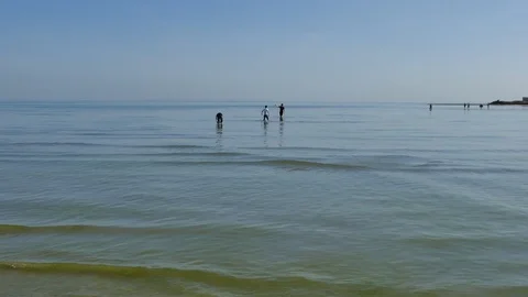 Crowd of people walking deep in the shallow sea waters to the nearby island Stock Footage 111667432