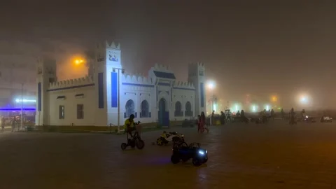 Crowd of people walking in a public square on a foggy night Stock Footage 202199736