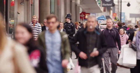 Crowd of people walking through British city shopping area &amp; police on patrol  Stock Footage 48117060