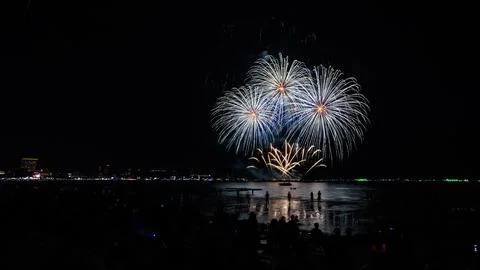 Crowd Of People Watching Fireworks Exploding Over Ocean From Beach At Night.. Stock Photos
