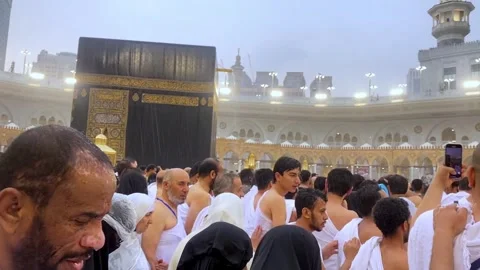 A crowd of pilgrims in ihram garments performing Tawaf around the Kaaba in the Stock Footage 345835780