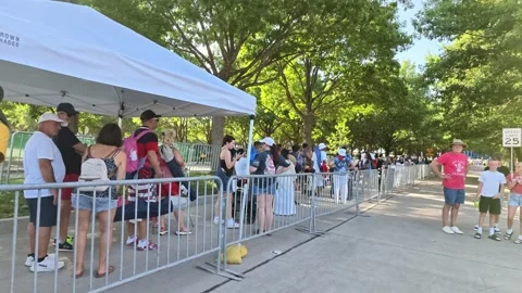 Crowd queuing behind metal barriers under white tent Stock Footage 340941101