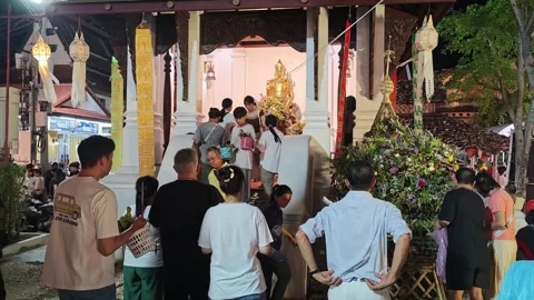 Crowd queuing at illuminated golden Buddha shrine during Inthakin Festival Stock Footage 337042615