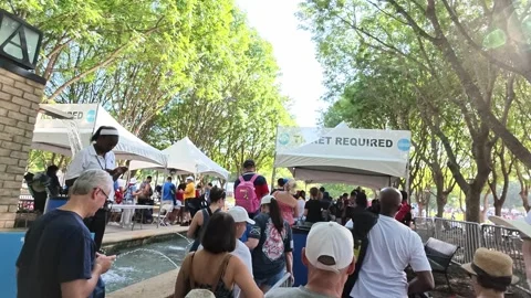 Crowd queuing at ticket tents in a park Stock Footage 340941126