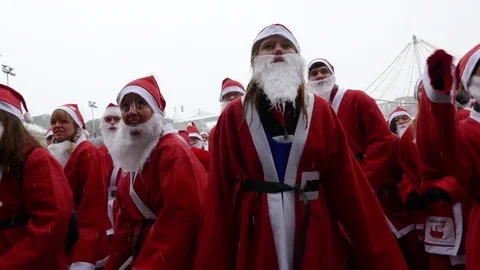 Crowd of Santa Clauses dancing in heavy snow, new year charity white background Stock Footage 70645489