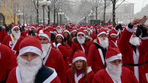 Crowd of Santa Clauses walking close to camera, heavy snow for new year charity Stock Footage 70645218
