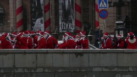 Crowd of Santa Clauses walking taking mobile picture in street, snow new year Stock Footage 70646376