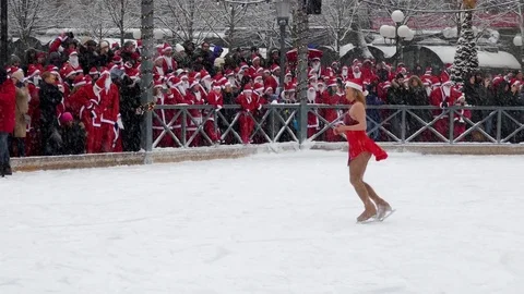 Crowd of Santa Clauses watching clapping for female Santa ice skating dance Stock Footage 70644874