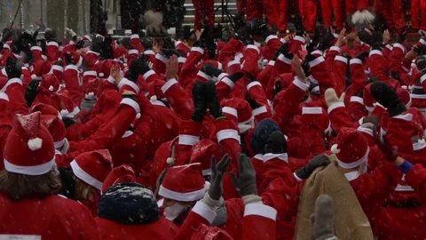 Crowd of Santa Clauses waving hands in air and clapping for new year charity Stock Footage 70642378