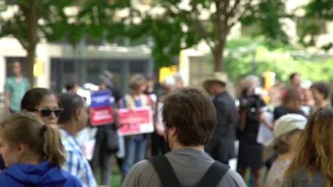 Crowd with signs protesting against Donald Trump at a park in Atlanta, US Stock Footage 76834640