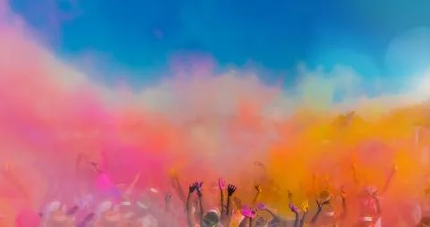 Crowd throwing bright coloured powder paint in the air, Holi Festival Dahan. Stock Photos