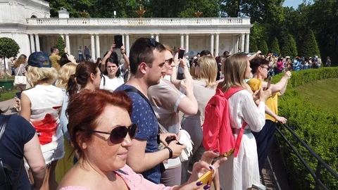 A crowd of tourists walking around Peterhof. People take selfies, are photogr Stock Footage 112344589