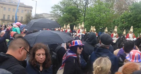 Crowd under umbrellas watching royal cavalry on coronation day Stock Footage 321017532