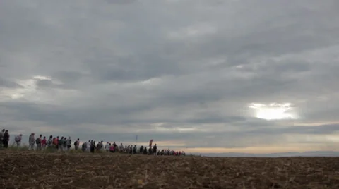 Crowd walking on the horizont through field Stock Footage 33828793