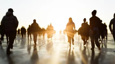 Crowd walking towards bright light at sunset Stock Illustration