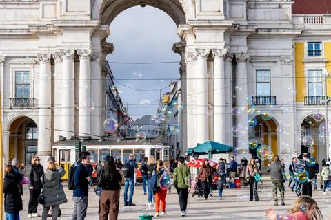Crowd walking under Praca do Comercio arch with bubbles Stock Photos