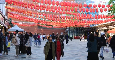Crowd walking under red Chinese lanterns in London Chinatown square Stock Footage 321032571