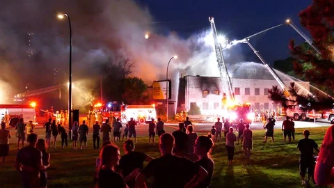 Crowd watching firefighters battling fire Stock Footage 115980645