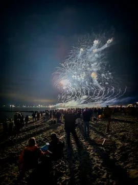 Crowd Watching Large Firework Display from Beach Фото