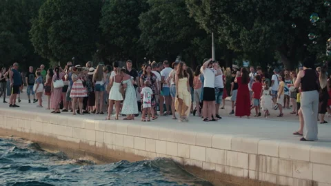 Crowd Watching Soap Bubbles on Waterfront Promenade Vídeo Stock 340324769