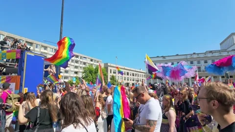 Crowd waving rainbow flags and dancing in city square parade 스톡 동영상 331448937