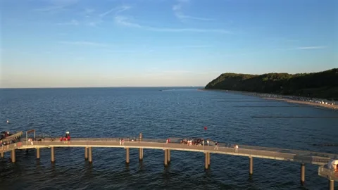Crowd wearing eclipse glasses gathers on curved pier platform overlooking calm Stock Footage 346357419