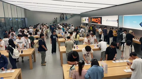 Crowded Apple Store filled with customers exploring new products on sleek wooden Stock Footage 339329503