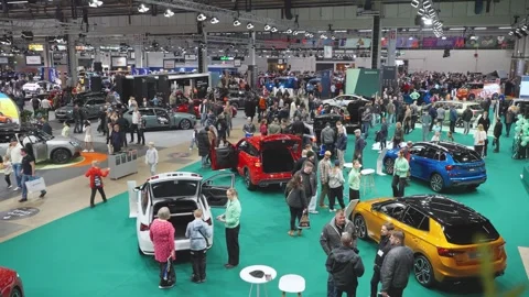 A crowded auto show with people exploring various car brands and models. Stock Footage 318675750
