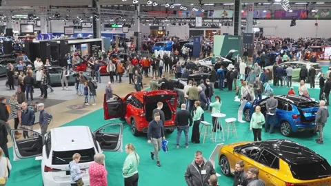 A crowded auto show with people exploring various car brands and models. Stock Footage 318675775