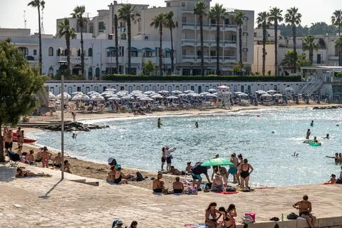 Crowded beach with umbrellas and swimmers 库存照片