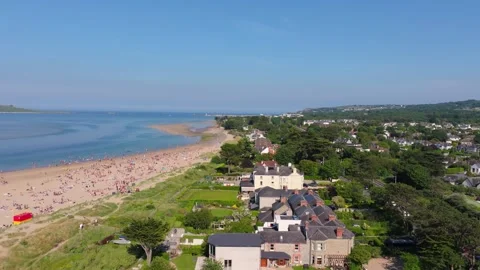 Crowded Irish Sand Spit beside Coastal Village, Aerial Fly Along Stock Footage 338077455