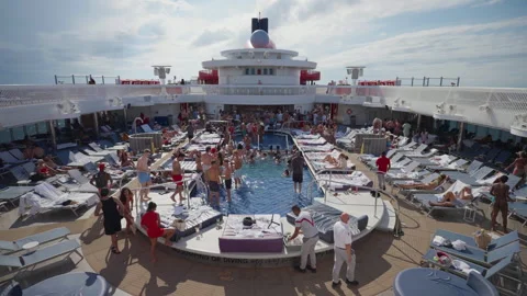 Crowded pool deck with passengers swimming and sunbathing on cruise ship. Stock Footage 340188210