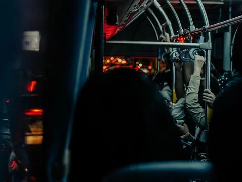 Crowded public bus interior with hanging handles and night city lights Foto stock